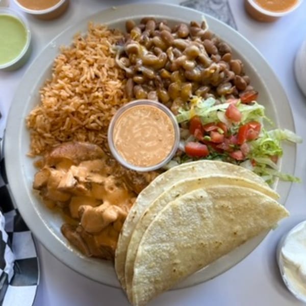A large plate of Mexican food with rice, beans, chicken in cream sauce, salad, and tortillas.