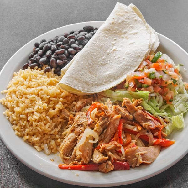 Mexican plate with a flour tortilla, seasoned rice, black beans, shredded chicken with peppers, lettuce, and pico de gallo.